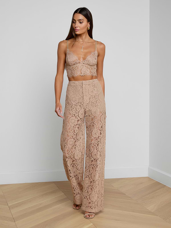 A woman wearing the Livvy Lace Trouser, styled with a matching nude floral lace crop top and nude heels, walks against a plain white background.