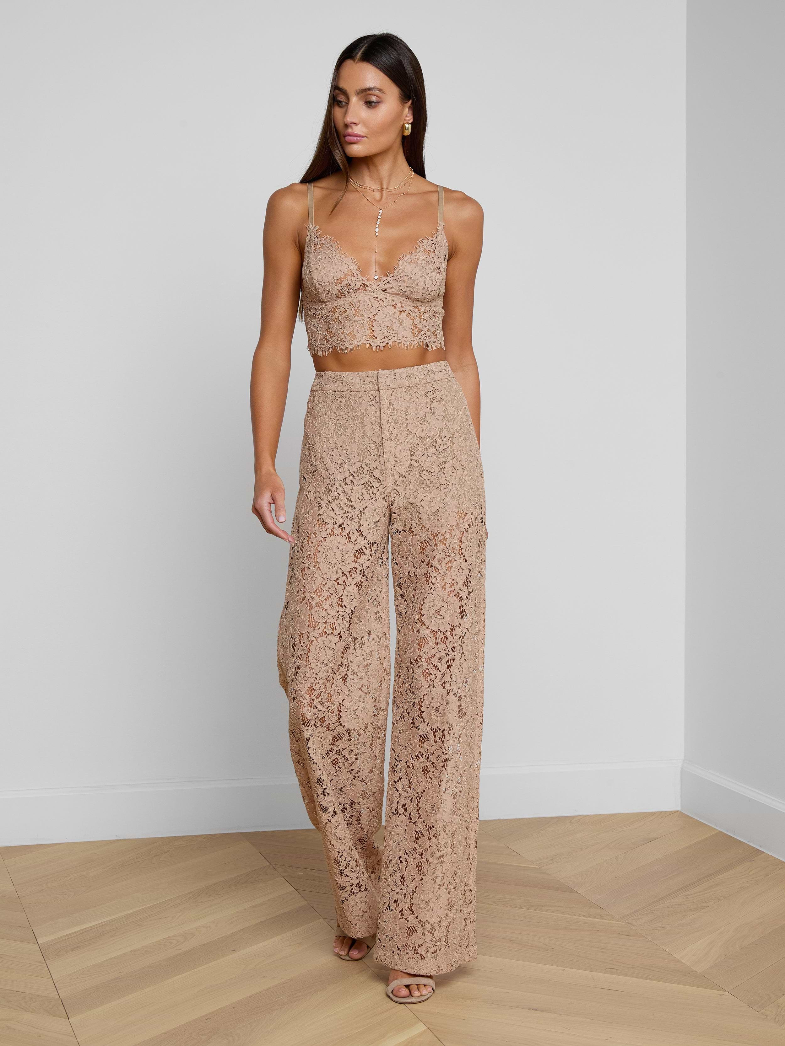 A woman wearing the Livvy Lace Trouser, styled with a matching nude floral lace crop top and nude heels, walks against a plain white background.