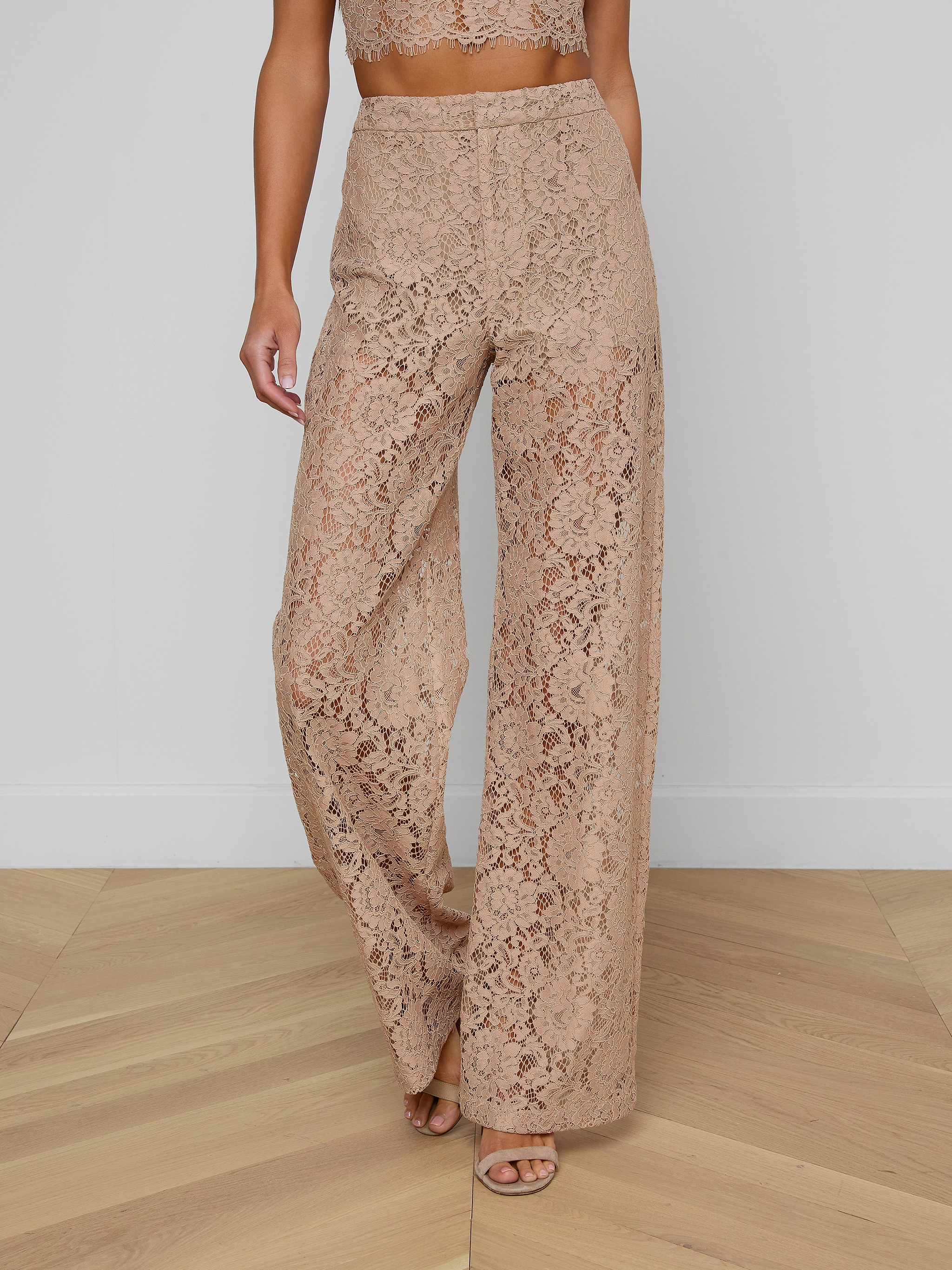 Model showcases the Livvy Lace Trouser, featuring a high-waisted, wide-leg silhouette in beige floral lace. Only her lower body is visible against a plain light background.