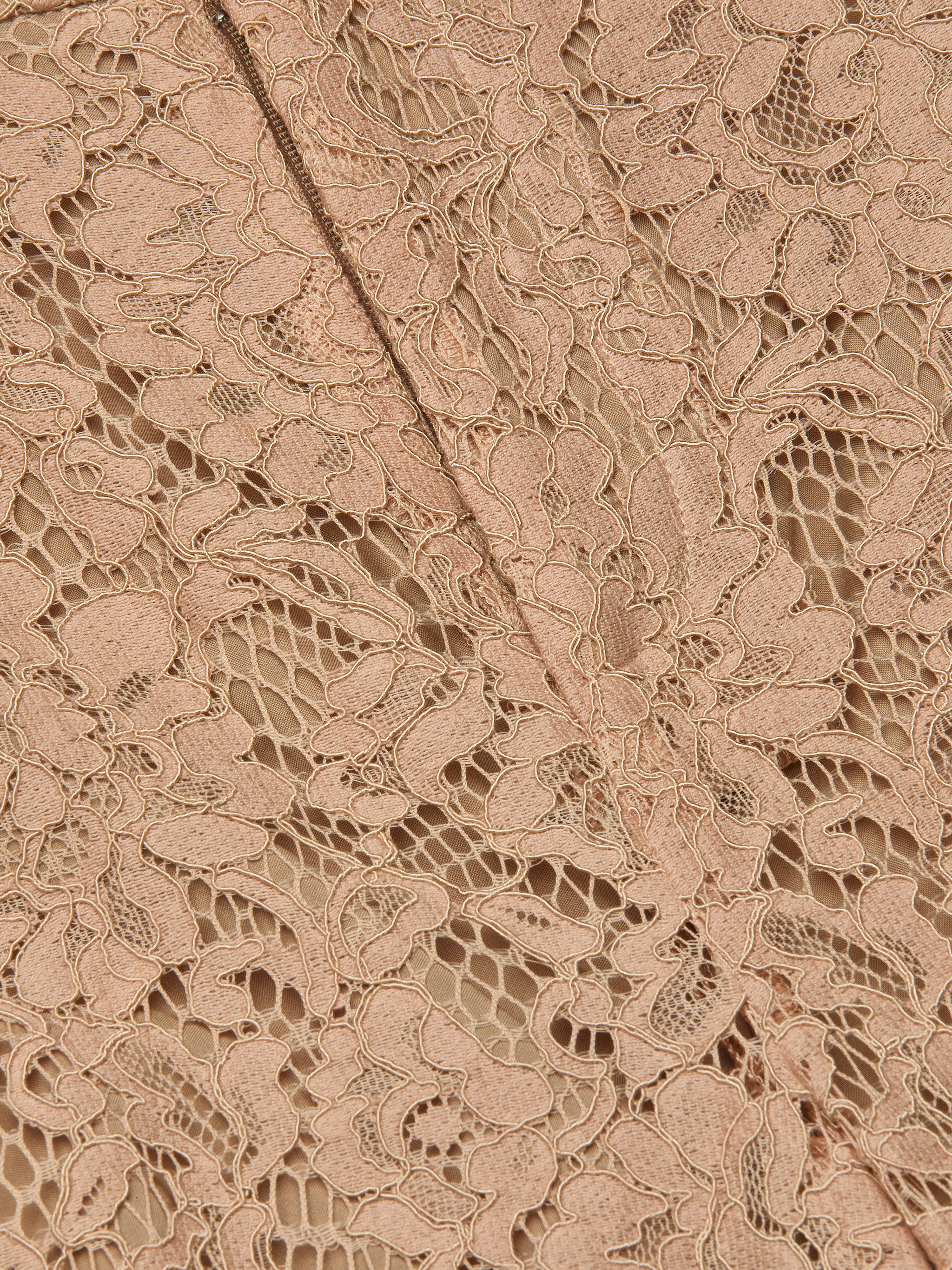 Close-up of the Livvy Lace Trouser featuring intricate beige floral lace fabric, a delicate pattern, and visible stitching running diagonally through the center.