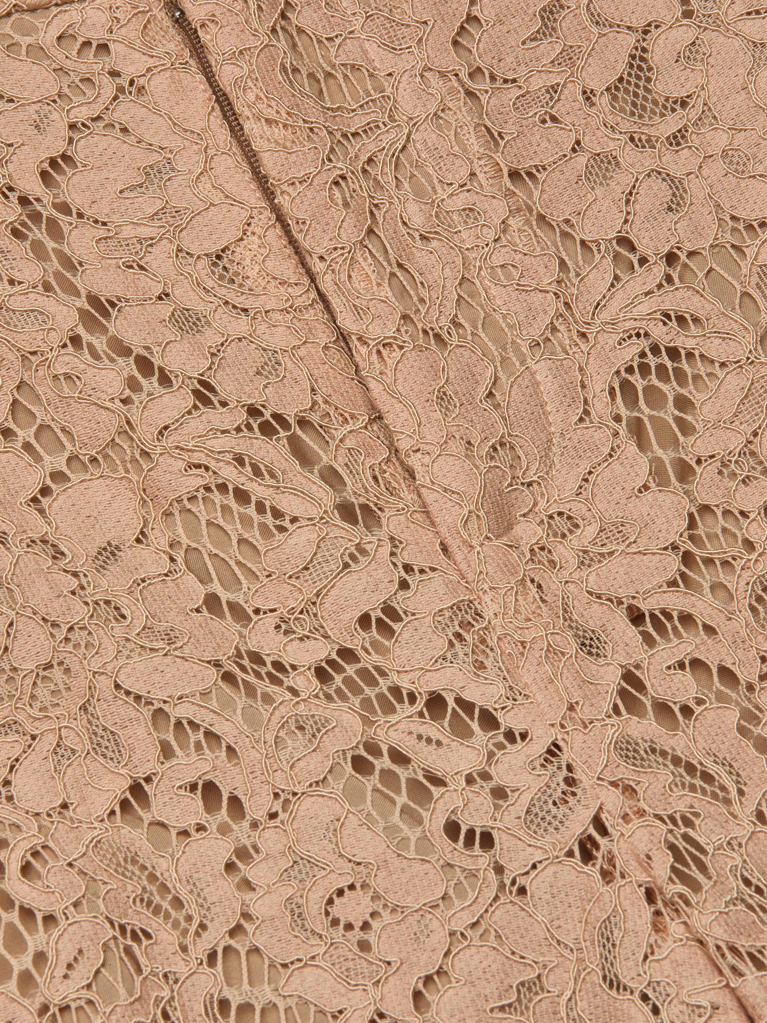 Close-up of the Livvy Lace Trouser featuring intricate beige floral lace fabric, a delicate pattern, and visible stitching running diagonally through the center.