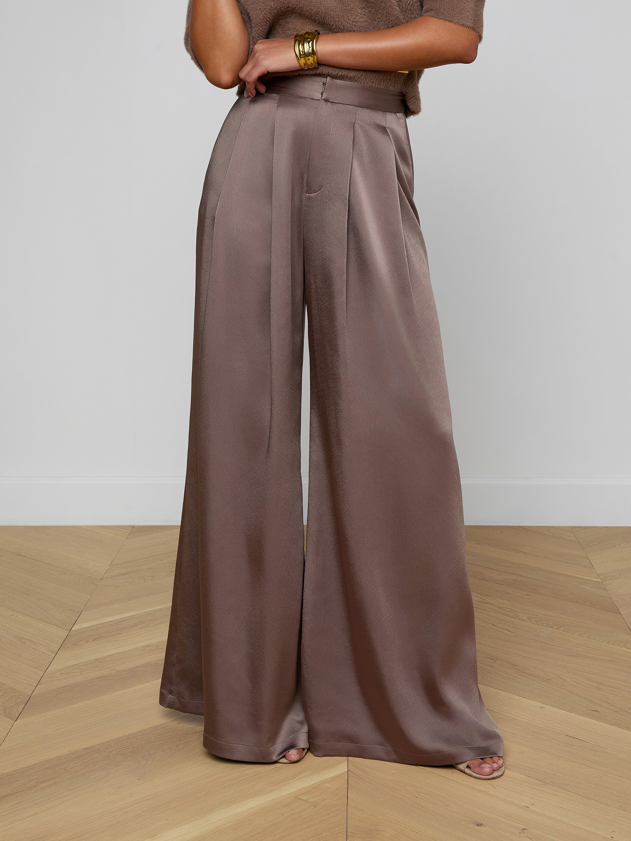 A person wearing the Aubrie Satin Pant in cardamon brown, paired with a coordinating brown top and gold bracelets on their wrist, stands against a light background.