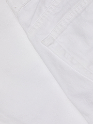 Close-up of the Krista Tapered Jean in white denim, focusing on the pocket and stitched seam details, with textured stretch denim fabric visible. The image highlights the weave and structure characteristic of these high-rise tapered leg jeans.