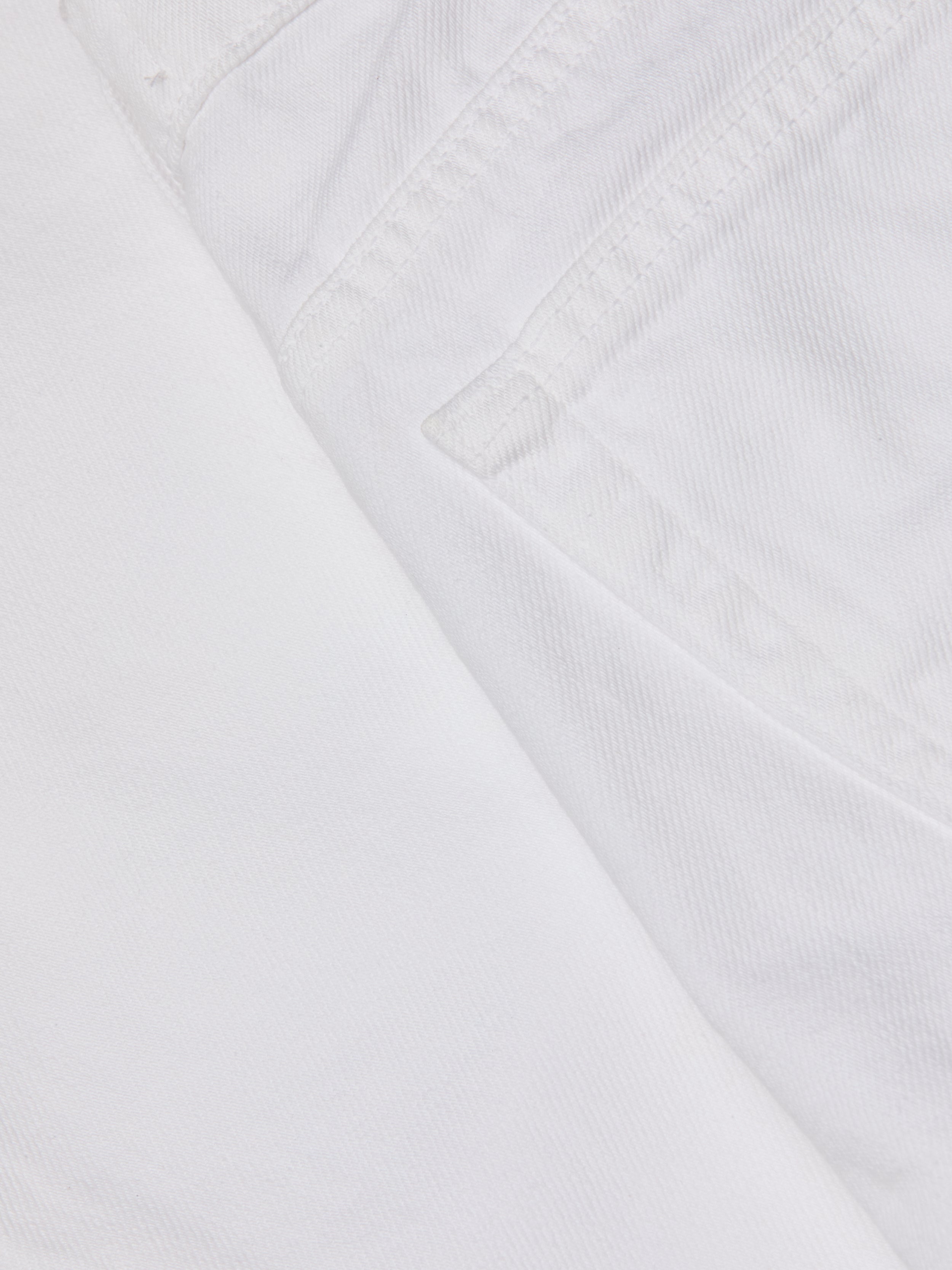 Close-up of the Krista Tapered Jean in white denim, focusing on the pocket and stitched seam details, with textured stretch denim fabric visible. The image highlights the weave and structure characteristic of these high-rise tapered leg jeans.