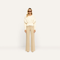 A person wearing a white cable-knit fringe sweater and tan Joanne Low-Rise Wide-Leg Jean.