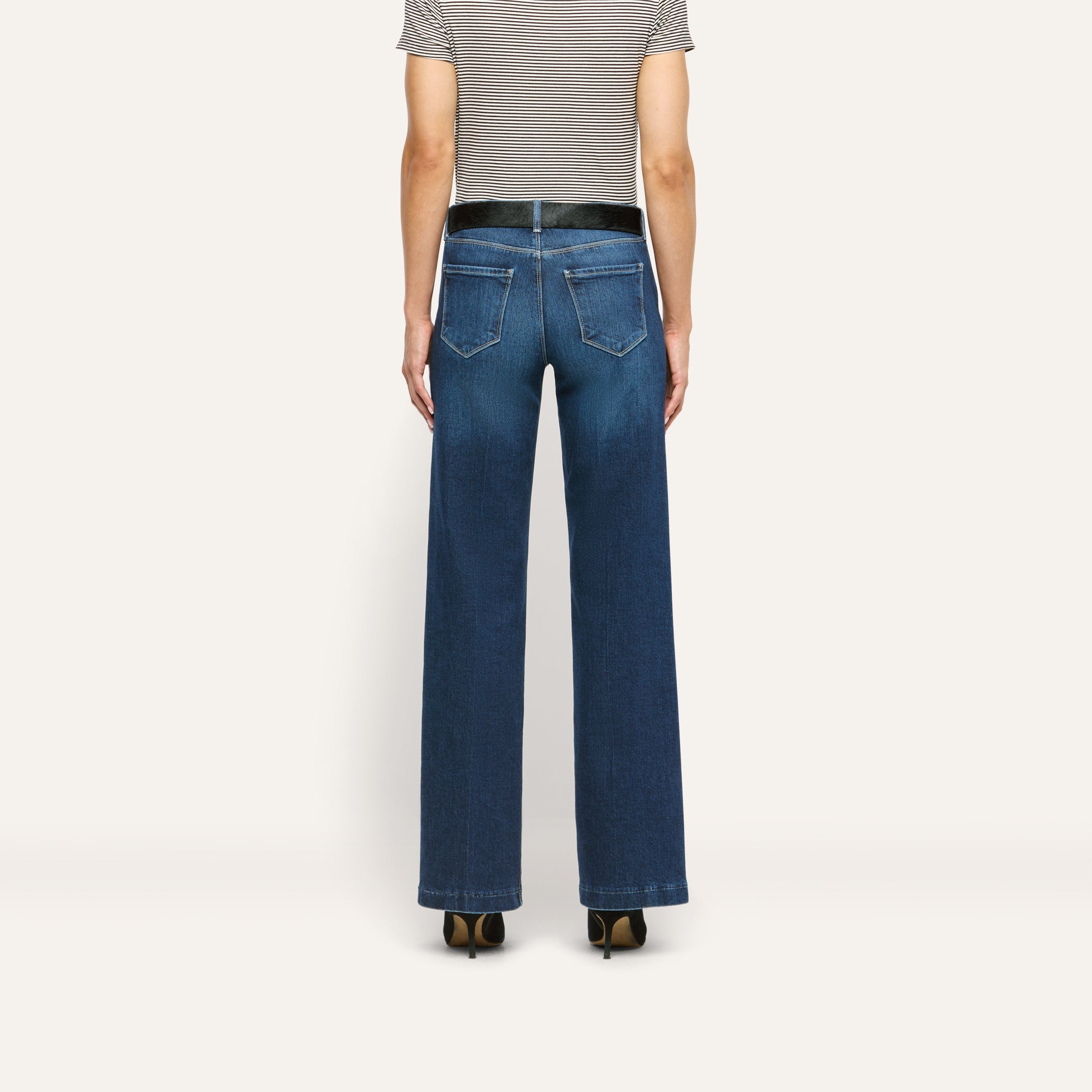Back view of Joanne Low-Rise Wide-Leg Jean in stretch denim, featuring a black belt, striped t-shirt, and black heels.