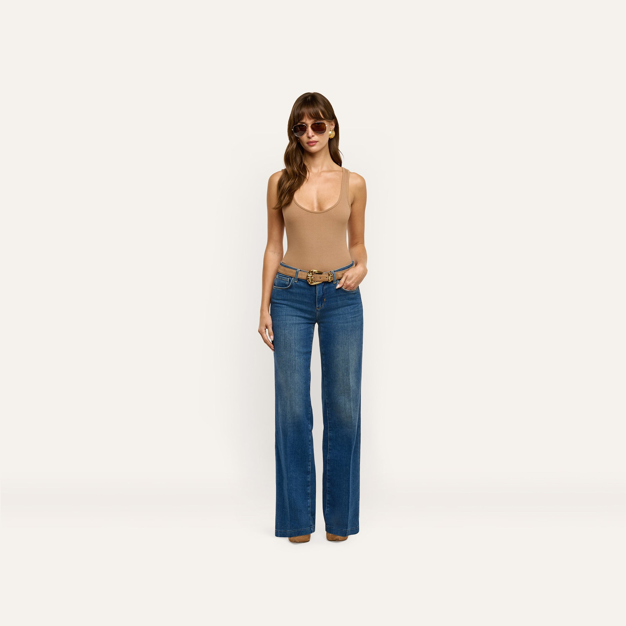 A person wearing a tan tank top, sunglasses, and Joanne Low-Rise Wide-Leg Jean in an indigo wash with a belt.