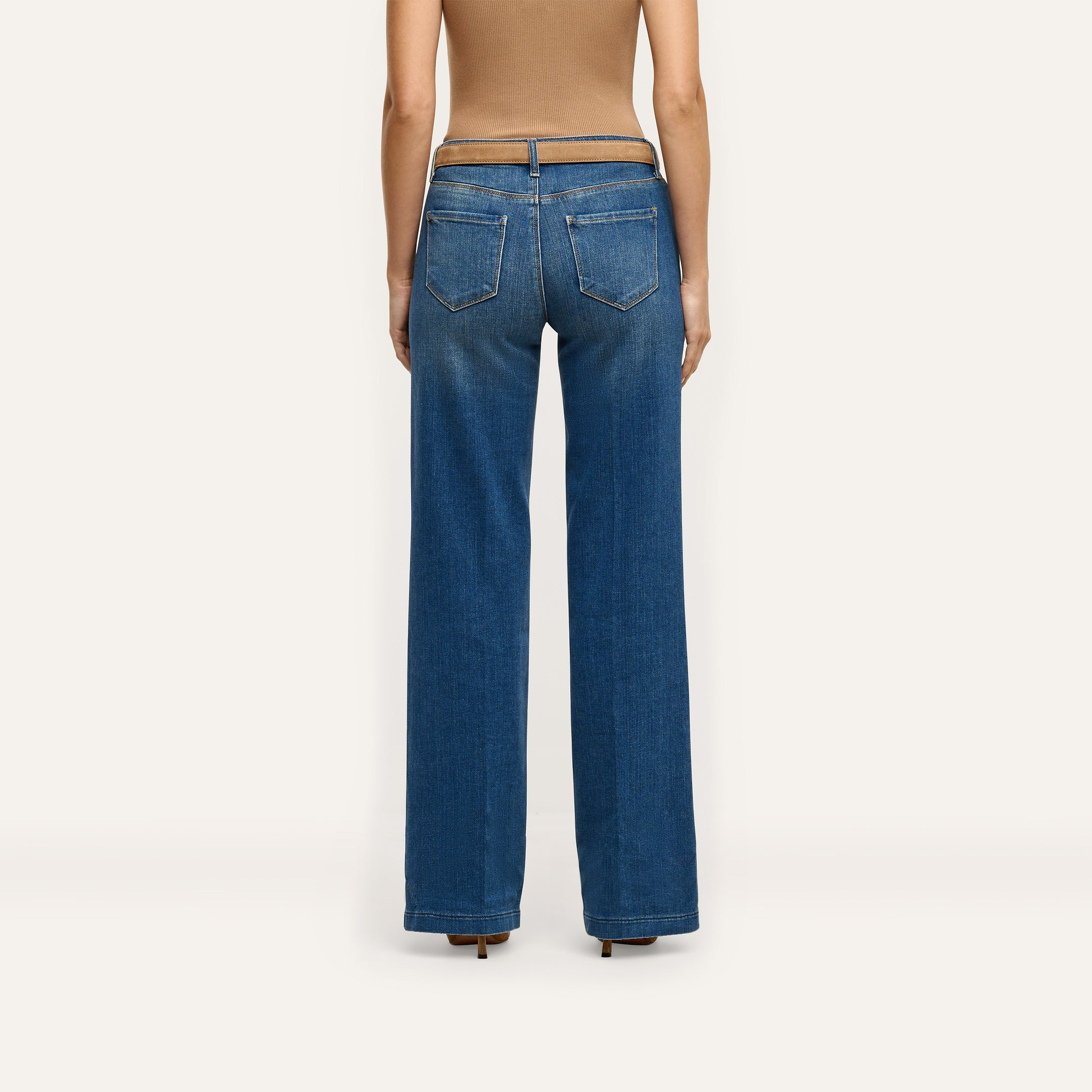 Back view of a person wearing Joanne Low-Rise Wide-Leg Jean in an indigo wash with a brown belt and a tan top.