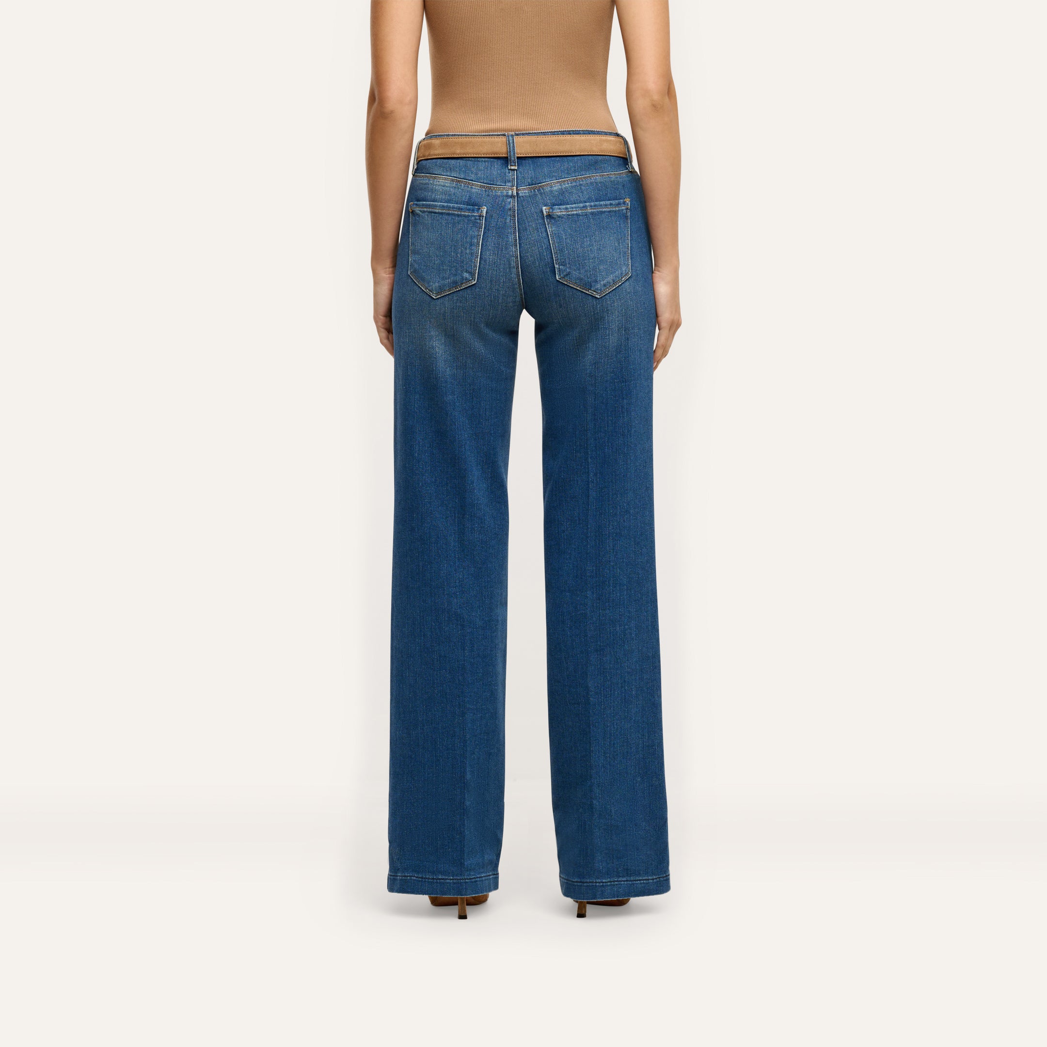 Back view of a person wearing Joanne Low-Rise Wide-Leg Jean in an indigo wash with a brown belt and a tan top.