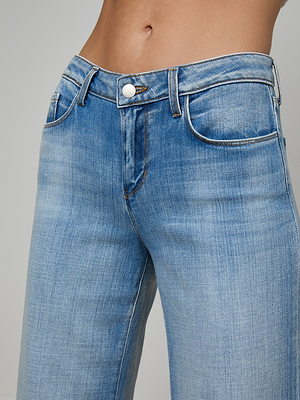 Close-up of a person wearing the Joanne Low-Rise Wide-Leg Jean, featuring a button and zipper closure, shown from the waist to upper thighs against a plain background.