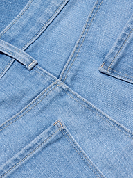 Gros plan sur le jean à jambe large et à taille basse Joanne en délavage indigo clair, montrant les coutures, la ceinture, le passant de ceinture et le haut des poches arrière. La texture et les coutures de ce jean à jambe large sont clairement visibles.