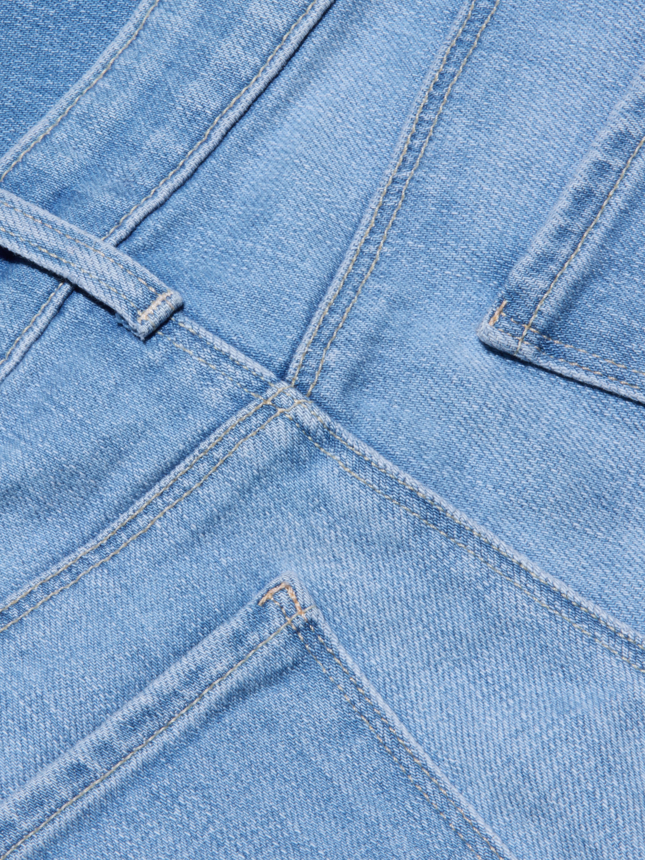 Gros plan sur le jean à jambe large et à taille basse Joanne en délavage indigo clair, montrant les coutures, la ceinture, le passant de ceinture et le haut des poches arrière. La texture et les coutures de ce jean à jambe large sont clairement visibles.