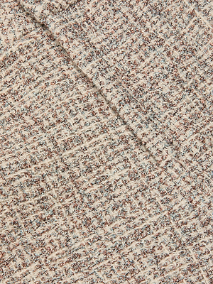 Close-up of the Italian tweed fabric used for the Lula Cropped Tweed Trouser in beige, brown, and grey grid-like threads, slightly folded to showcase its thickness and textured surface.