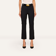 A woman, shown from the shoulders down, wears the Ketra Bootcut Trouser in black with slant pockets, a black belt with a large gold buckle, black heels, and a white top.