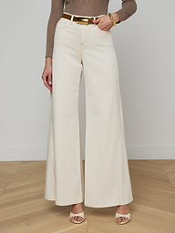 A person wearing the Beau Wide-Leg Jean in cream stretch cotton twill, paired with a brown long-sleeve top, beige heeled sandals, and a gold bracelet, standing against a plain white background.