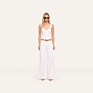 A woman in sunglasses, a white tank top, the Beau Wide-Leg Jean with a brown belt, and tan pointed shoes stands against an off-white background.