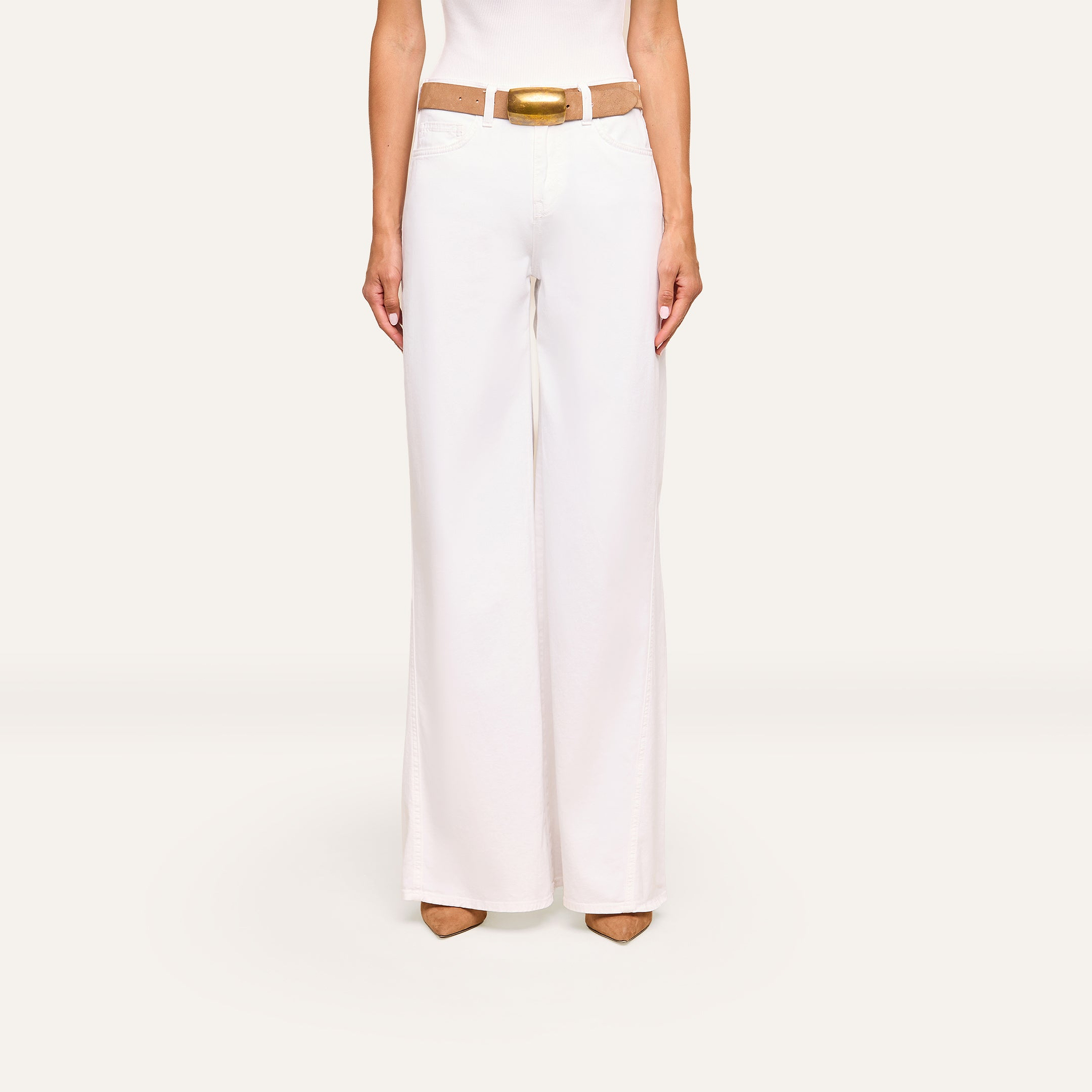 Wearing the Beau Wide-Leg Jean with a tan belt and tan pointed-toe shoes, a person stands against a plain light background, visible from torso to legs.