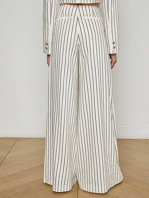 A person faces away, dressed in the Kingston Striped Wide-Leg Pant by L'AGENCE Sale—high-waisted, floor-length trousers with thin vertical pinstripes—styled with a matching blazer for a chic, sophisticated look.