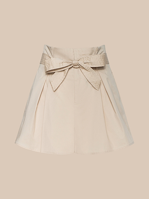 The Damira Poplin Short, a beige high-waisted stretch poplin short with a self-tie belt bow, pleated details, and a flared silhouette, is shown on a matching beige background.