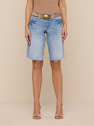 A person wearing a tan sleeveless top, a tan belt, open-toe heels, and the Elise Jean Bermuda Short—a relaxed fit, light blue, knee-length all-cotton denim short with a raw hem—stands against a plain white background.