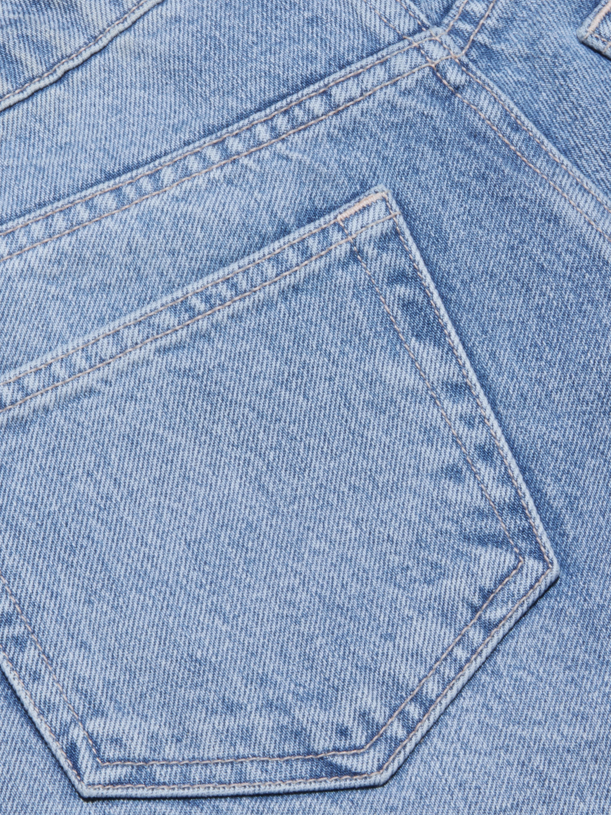Close-up of light blue all-cotton denim fabric showing a pocket and visible stitching details on the Elise Jean Bermuda Short.