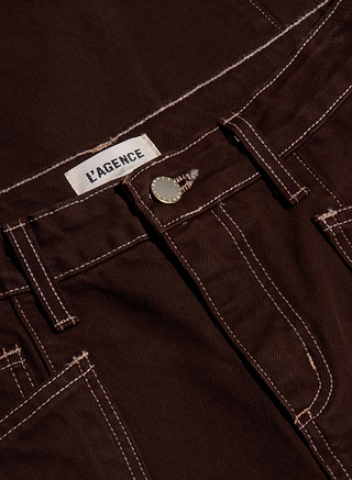 Close-up of the Cody Cropped Barrel-Leg Jean, featuring brown non-stretch denim with white stitching, metal button, belt loops, and a visible L’AGENCE label. Expertly tailored in a flattering high-rise silhouette, this barrel-leg jean highlights thoughtful design details.