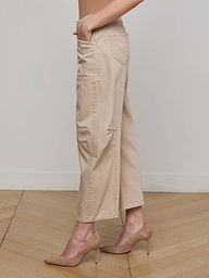 A person, shown from the waist down in profile against a plain white background, wears Cody Cropped Barrel-Leg Jeans with patch pockets and tan high-heeled shoes.