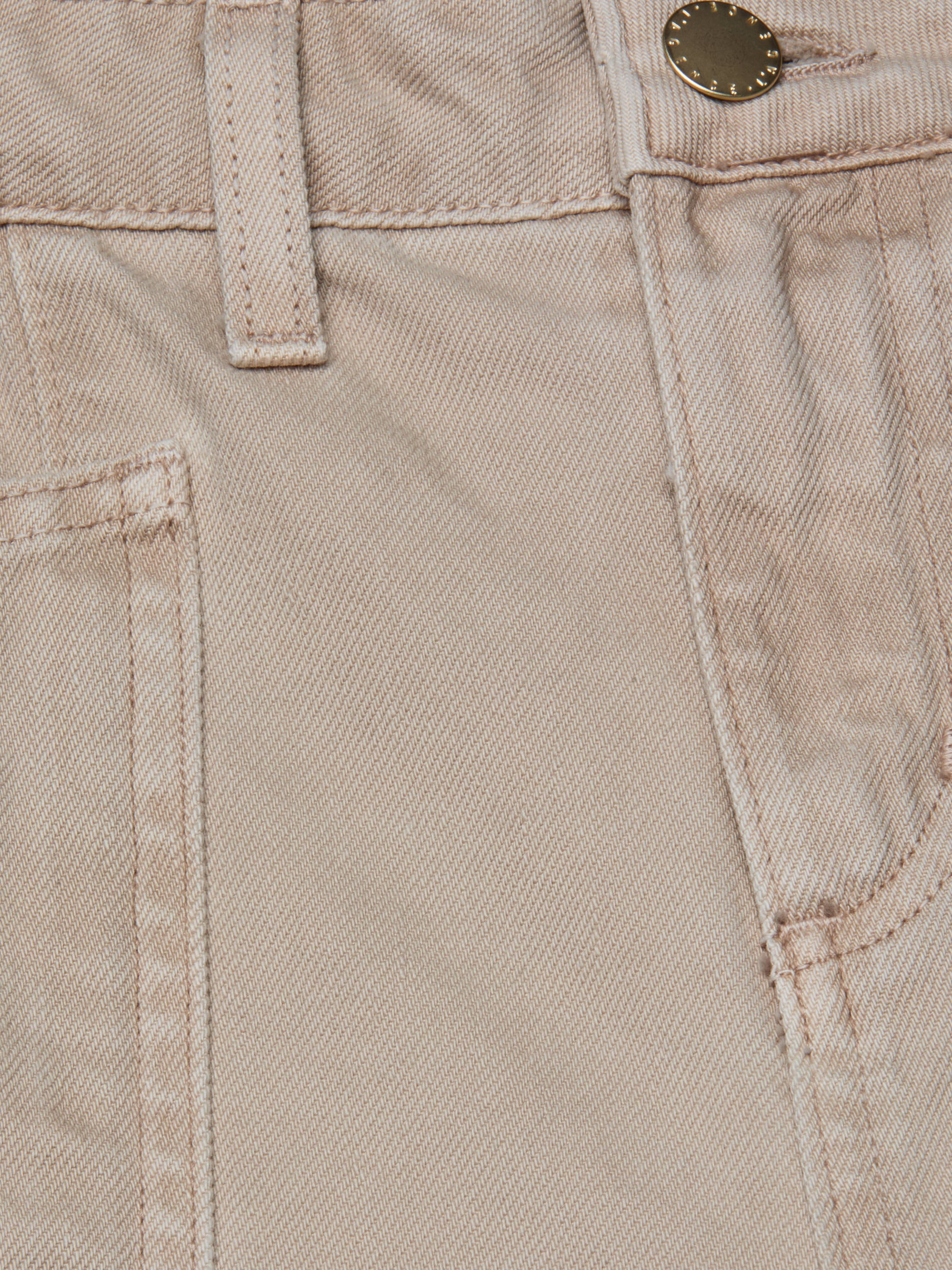 Close-up of the Cody Cropped Barrel-Leg Jean in beige, made from all-cotton denim, showing a front pocket, belt loop, waistband stitching, and a metal button.