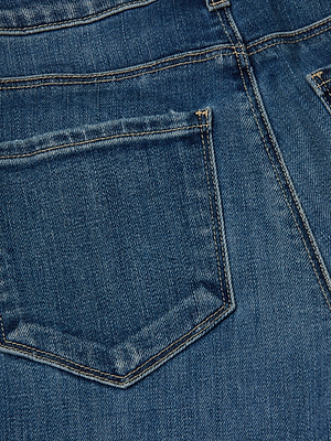 Close-up of the back pocket on the L'AGENCE Cara Low-Rise Bootcut Jean, highlighting detailed stitching and blue stretch denim fabric texture.