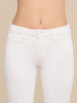 لقطة مقربة لشخص يرتدي بنطال جينز «Cara Low-Rise Bootcut» باللون الأبيض، والذي يتميز بجيوب أمامية، وقماش دنيم مرن، وإغلاق بأزرار. يبرز هذا البنطال الجينز الخصر وأعلى الساقين على خلفية بيج سادة.
