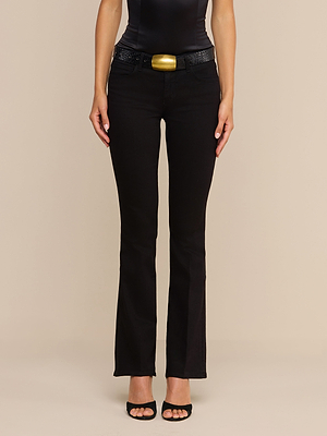 Une personne vêtue dun haut noir sans manches, dun jean bootcut taille basse « Cara » agrémenté dune large ceinture texturée dotée dune grosse boucle dorée, et descarpins noirs à bout ouvert, se tient debout devant un fond beige uni.