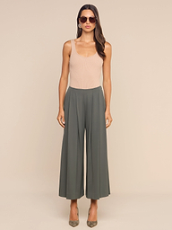Woman wearing sunglasses, a beige sleeveless top, and high-rise, wide-leg gray Novalynn Cropped Pleated Pant stands facing forward against a plain white background. She has long brown hair and is wearing pointed-toe heels.