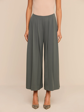 A person wearing the Novalynn Cropped Pleated Pant in olive green—styled high-waisted with a wide-leg silhouette—paired with a sleeveless beige top and gray high-heeled shoes stands against a plain light background.