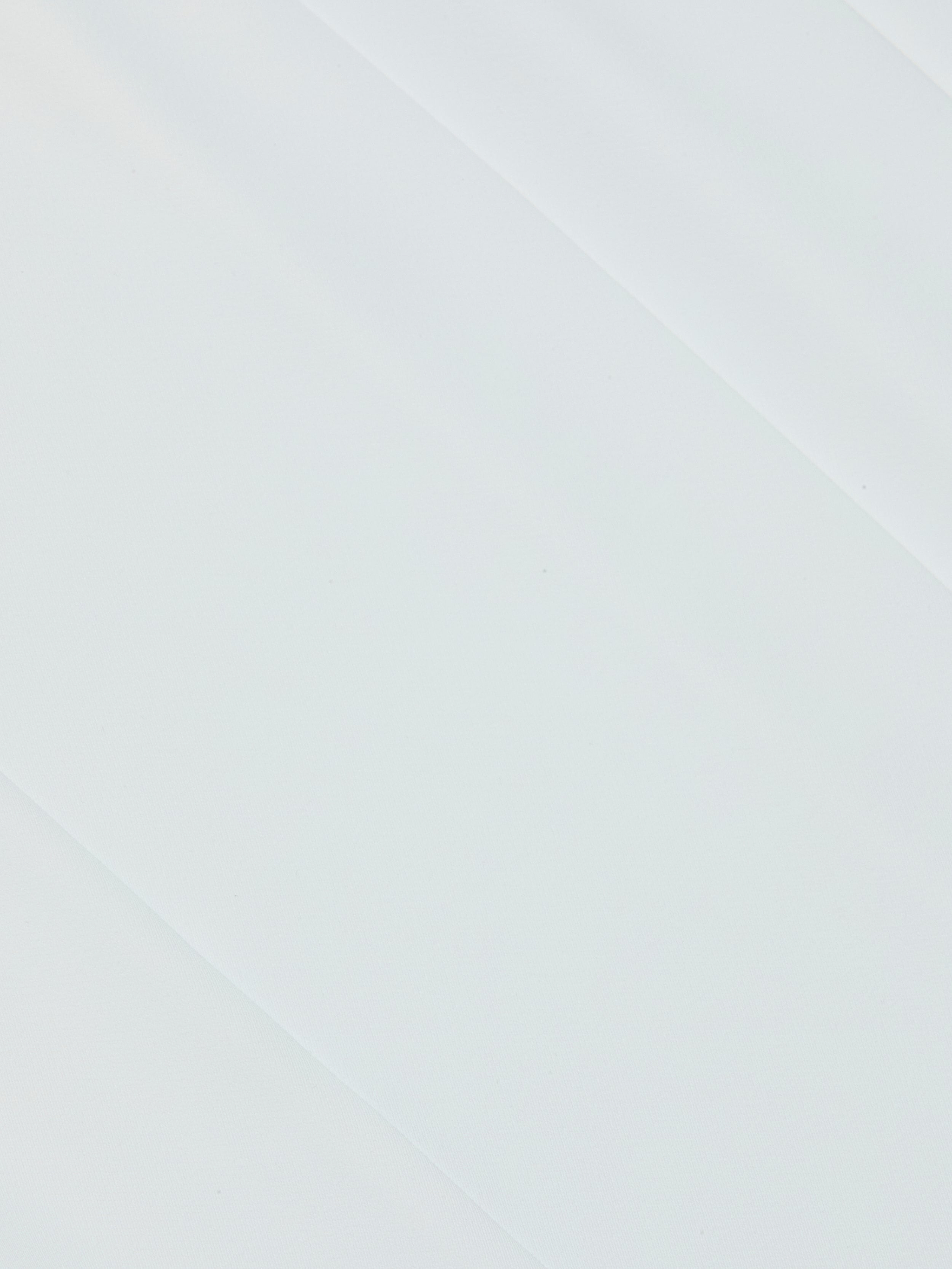 White surface with subtle diagonal shadows and texture, capturing the minimalist and clean aesthetic reminiscent of the polished design found in the Novalynn Cropped Pleated Pant.