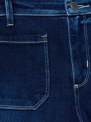Close-up of the front pocket and waistband of the Noya Cropped Slim Flare Jean in dark blue wash, featuring visible white stitching and a metal button.