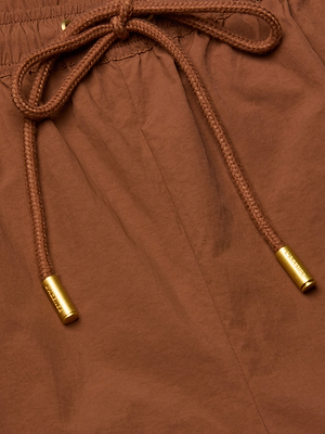 Close-up of the Mariko Jogger in brown, made from water repellent nylon with an elastic waistband and a drawstring finished with gold metal aglets.
