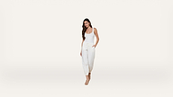 A woman wearing a white tank top and white drawstring pants stands against a plain white background, with her left hand in her pocket and wearing strappy nude heels.