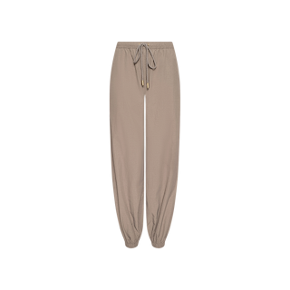 The Mariko Jogger, shown here in beige and crafted from lightweight nylon, features an elastic waistband with a drawstring tie and elasticized cuffs at the ankles. Displayed on a white background, these water-repellent jogger-style pants provide comfort and practicality for everyday wear.