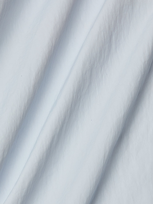 Close-up of white, softly crumpled water-repellent nylon with gentle folds and subtle shadows creates a smooth, textured look—ideal for the modern Mariko Jogger.