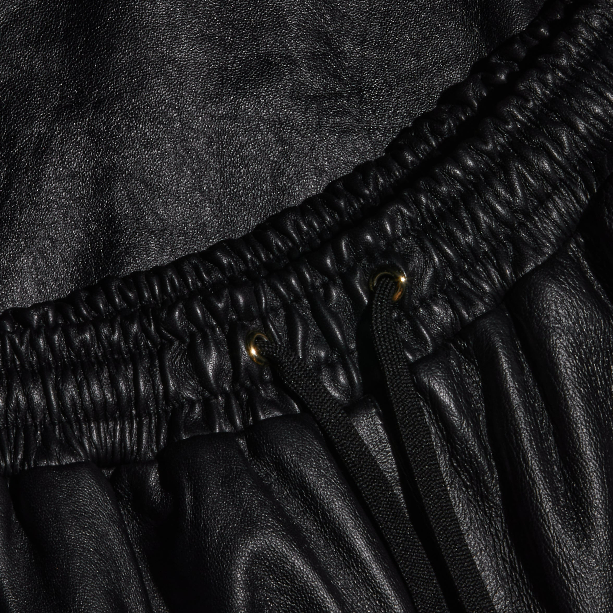 Close-up of the Mariko Leather Jogger in black lambskin, featuring an elastic waistband, metal eyelets, and black drawstrings.