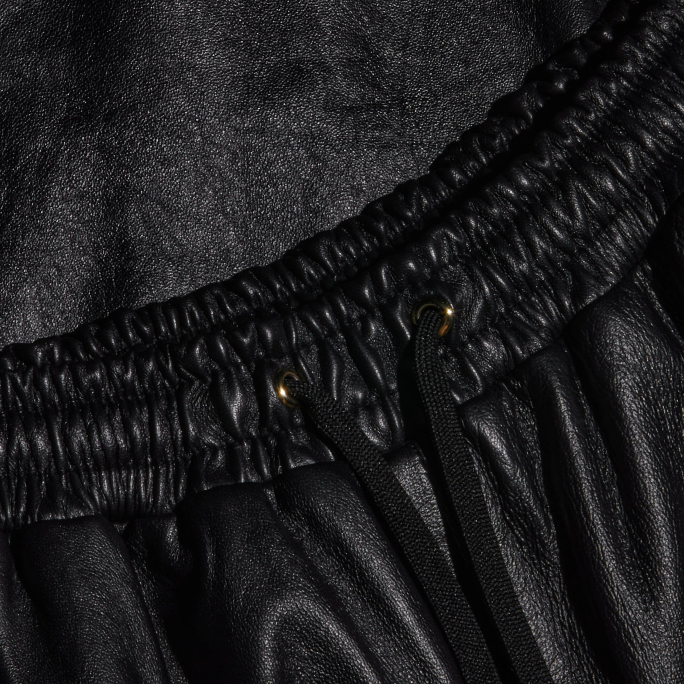 Close-up of the Mariko Leather Jogger in black lambskin, featuring an elastic waistband, metal eyelets, and black drawstrings.