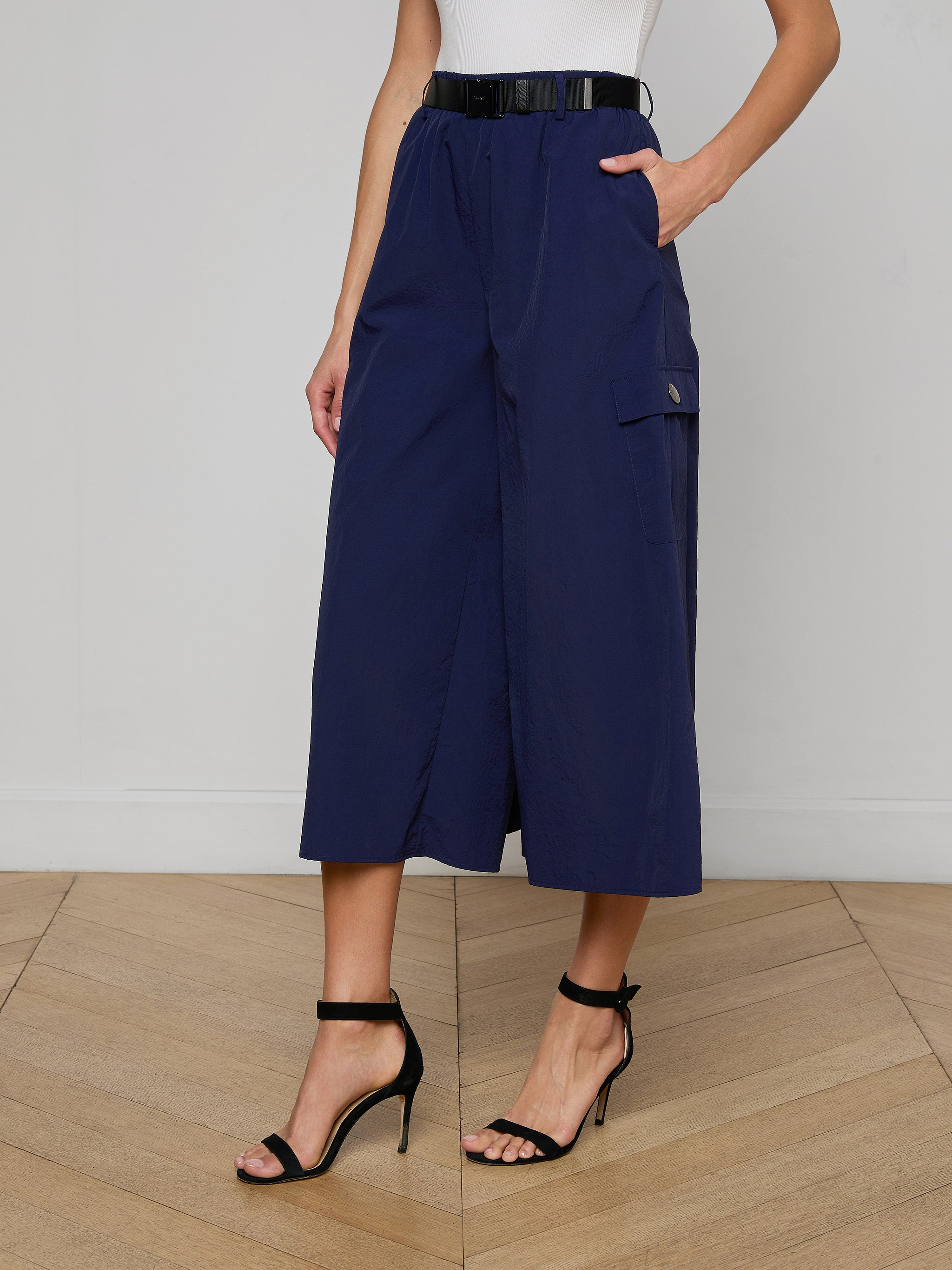 A person wearing the Shoda Cropped Wide-Leg Pant in navy blue with a black belt and black high-heeled sandals, standing against a plain light background.