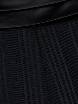 Close-up of the L'AGENCE Minerva Cummerbund Trouser in black fabric, showcasing diagonal and vertical textured stripes and a smooth, shiny cummerbund waistband folded at the top edge.
