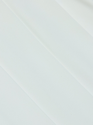 Close-up of the Naamah Pleated Short’s smooth, white fabric with subtle diagonal folds and gentle shadows, highlighting its wrinkle-resistant and minimalistic texture.