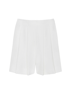 The Naamah Pleated Short features a white high-waisted tailored design with front pleats in wrinkle-resistant fluid suit fabric, shown on a plain white background—perfect for your resort wardrobe.