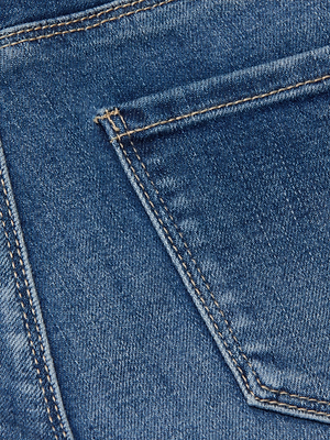 Close-up of blue stretch denim fabric showing the corner of a Celestia Slim-Leg Jean back pocket with visible stitching.