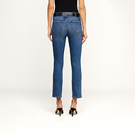 A person is shown from the back against a plain beige background, wearing Celestia Slim-Leg Jeans in an indigo wash, a black belt, and black heeled sandals.
