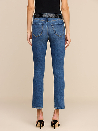 A person is shown from the back against a plain beige background, wearing Celestia Slim-Leg Jeans in an indigo wash, a black belt, and black heeled sandals.
