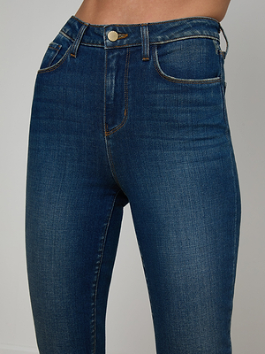 A close-up of a person wearing the Celestia Slim-Leg Jean, featuring high-rise, slim fit, front pockets, belt loops, button closure, and stretch denim that highlights the sleek silhouette around the waist and upper thighs.