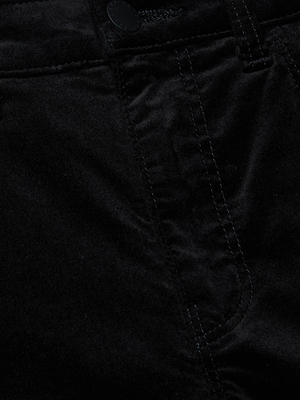 Close-up of the front section of L'AGENCE Celestia Velvet Slim-Leg Jean, featuring a button, visible stitching, and part of a pocket. The stretch velvet fabric and seams highlight its flattering fit.